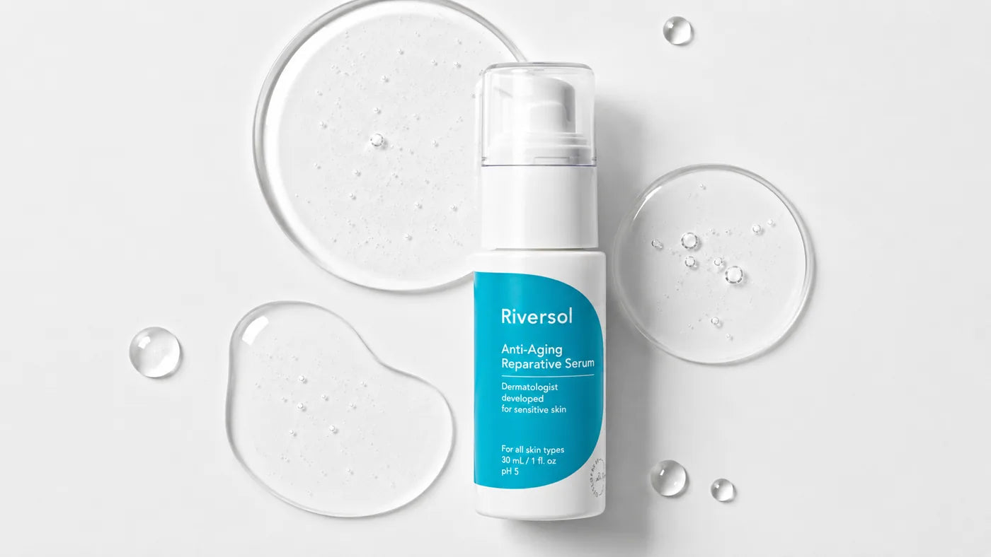 Anti-Aging Reparative Serum bottle styled with fresh orange slices on a clean white background